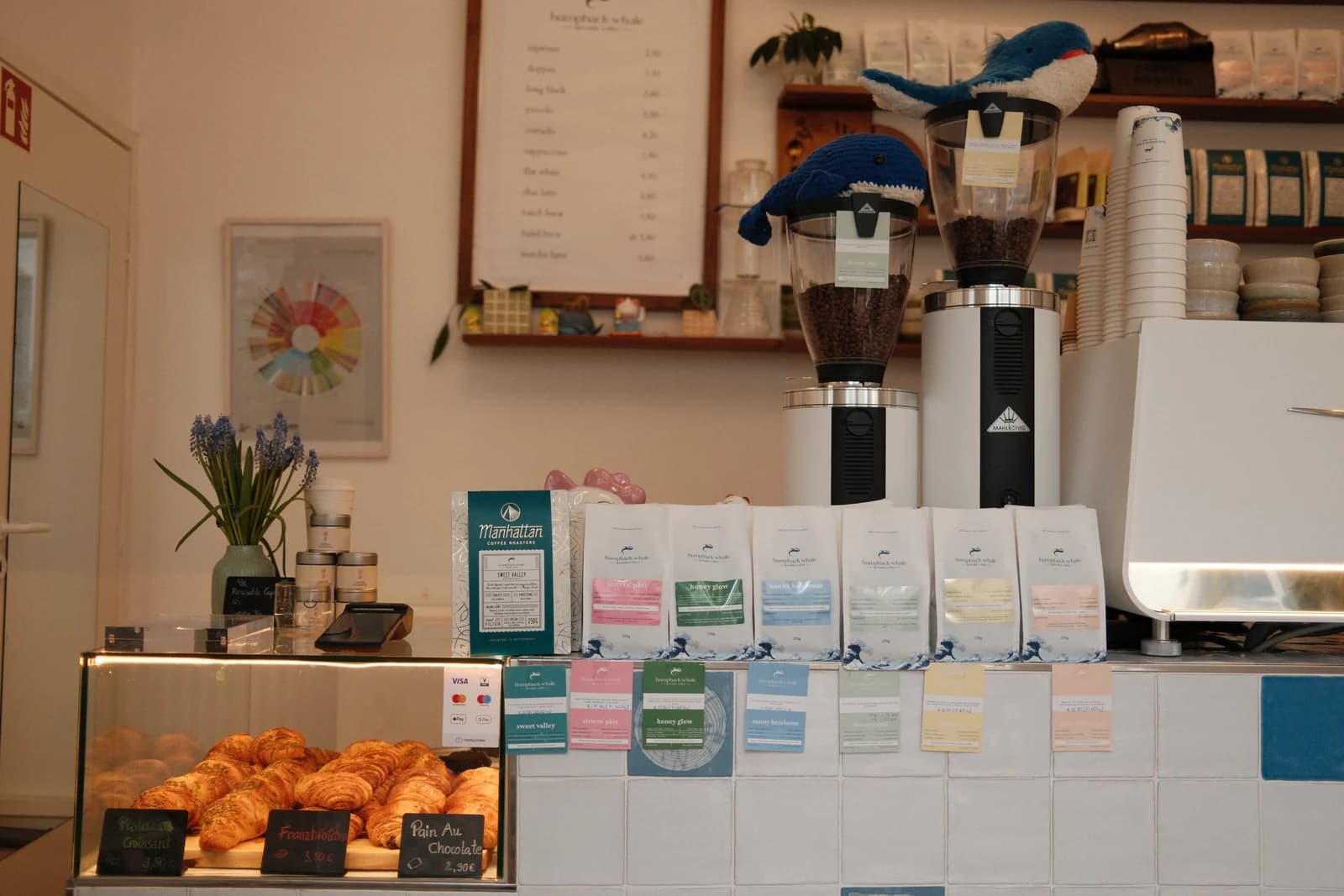The Humpback Whale café counter in Munich — pastries, grinders, and a row of single-origin coffee bags