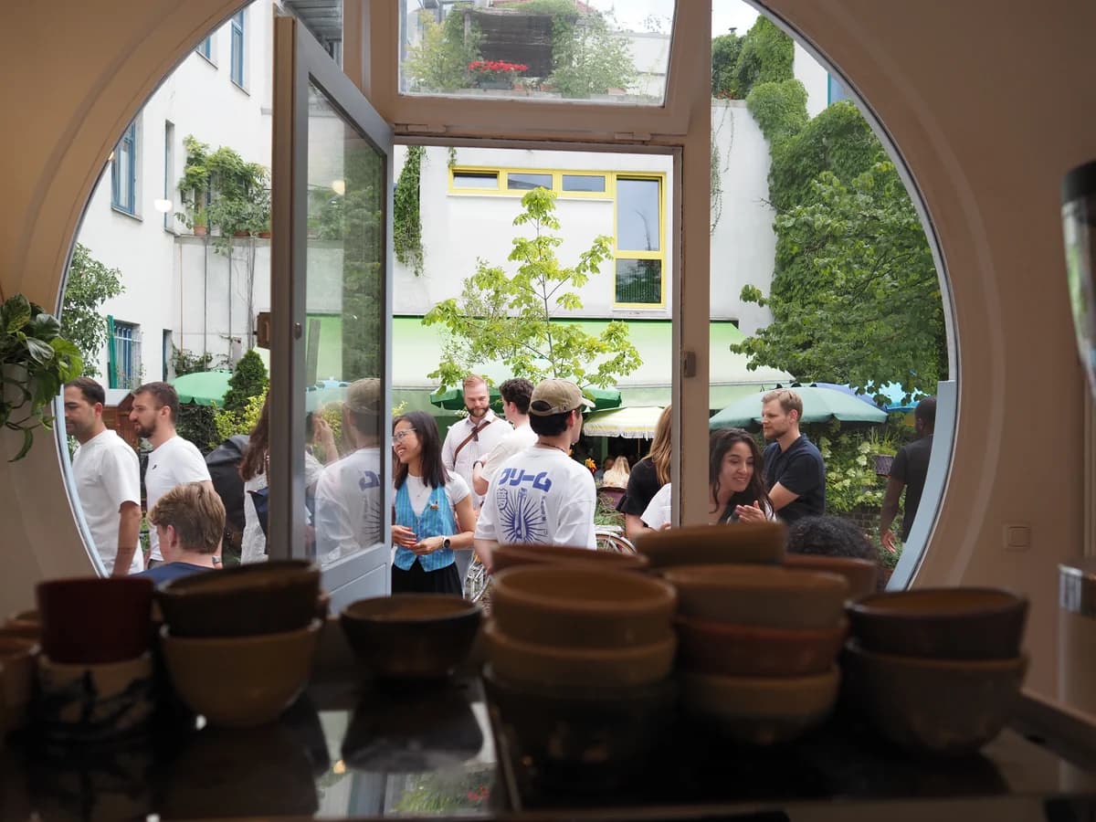 Handmade ceramic cups by the café's porthole doorway, looking out to a busy Amalienpassage courtyard in Munich